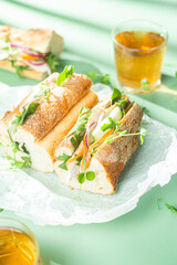 Sandwich with chicken, cucumber and arugula on a green background