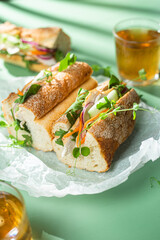 Sandwich with chicken, cucumber and arugula on a green background