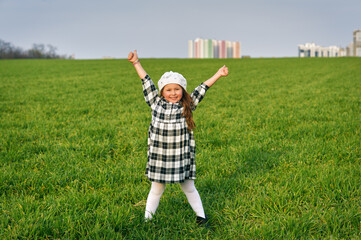 Happy little girl on a green meadow in the countryside. .