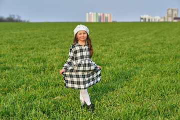 Happy little girl on a green meadow in the countryside. .