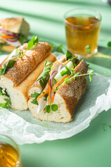 Sandwich with chicken, cucumber and arugula on a green background