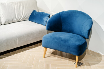 Blue armchair in retro style made of velour material on the background of a white sofa. Close-up