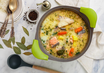 Creamy fish soup with salmon, potatoes, onions, carrots, parsley and spices in a saucepan. Kalakeitto. Lohikeitto . Traditional dish of the Finnish cuisine. Scandinavian dish. Top view - 485064483