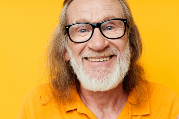 elderly gray-haired man with glasses face close-up yellow background