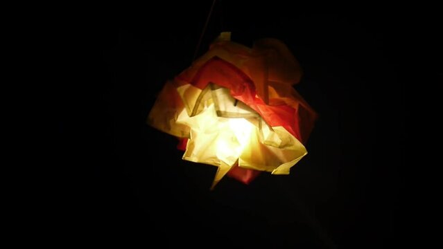 light bulb in a homemade lampshade in the dark outside