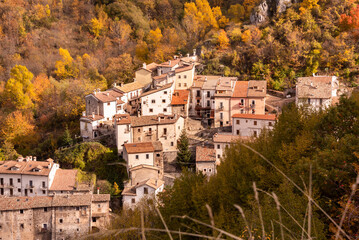 Fototapeta na wymiar Small village in autumn lanscape with colorful trees in Italy