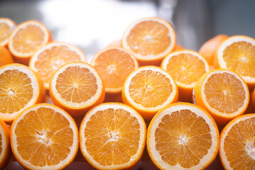 Many  fresh, juicy oranges cut half lies by rows on table. Wonderful, fresh juice from fruits drink every day health and replenish body with vitamins. Close-up