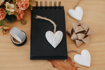 notebook with black sheets with copy space, bouquet of flowers and a white heart.