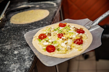 hand of chef baker making pizza at kitchen. Put on landing shovel and send it to the oven.