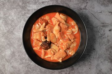Ration of callos a la madrileña in a black plate on a gray background