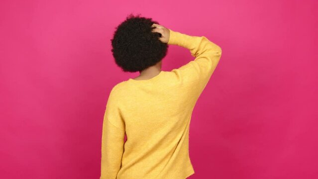 Young African American woman on back position looking back while scratching head over isolated background