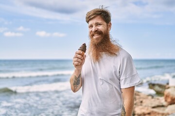 Fototapeta na wymiar Young redhead man smiling happy eating ice cream at the beach.