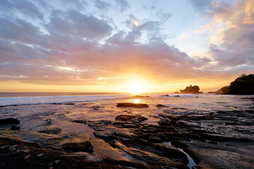 Beautiful balinese landscape. Ancient hinduism temple Tanah lot on the rock against sunset sky. Bali Island, Indonesia.