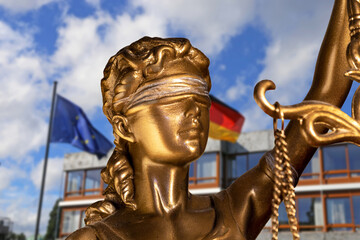 Symbolbild: Nahaufnahme einer Justitia, im Hintergrund das Bundesverfassungsgericht in Karlsruhe...