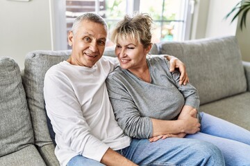 Senior caucasian couple smiling happy and hugging sitting on the sofa at home.