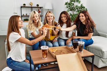 Group of young woman friends smiling happy eating pizza at home.