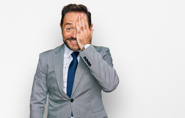 Middle age man wearing business clothes covering one eye with hand, confident smile on face and surprise emotion.