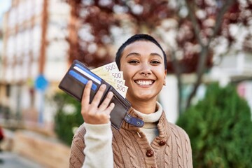 Beautiful hispanic woman with short hair smiling happy outdoors holding wallet with norwegian...