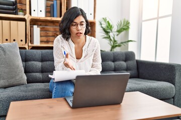 Young latin woman having psychology online session using laptop at psychology center