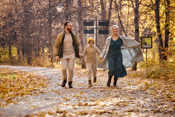 Excited caucasian family running, having fun in the park, autumn season, sunny day. cheerful positive spend vactions holidays on fresh air, smiling and laughing. family, children, love, emotions