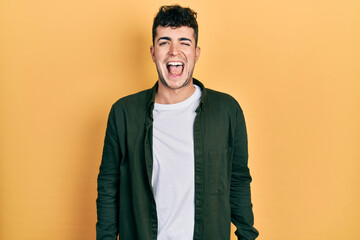 Young hispanic man wearing casual clothes winking looking at the camera with sexy expression,...