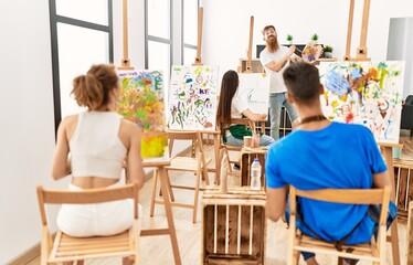 Group of people smiling happy drawing in paint class at art studio.