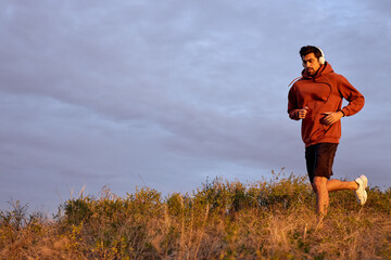 Sportive male during morning jogging outdoors in nature. Fitness, sport, exercising and workout in field concept. Training on fresh air alone, strong and fit, athletic, in sportswear