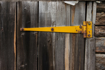 Painted yellow door hinges on garage door. Old wooden boards. Background. Close-up.