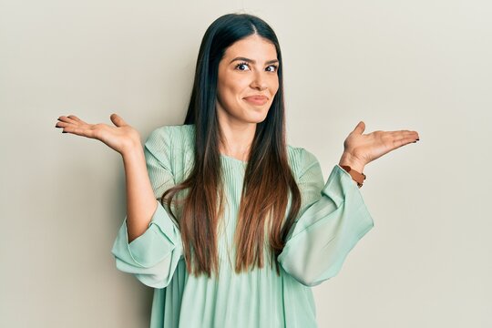 Young hispanic woman wearing casual clothes clueless and confused with open arms, no idea and doubtful face.