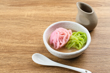 Kue Putu Mayang is traditional Indonesian snack made from rice flour strands curled up into a ball, served with coconut milk and palm sugar. Selected focus.
