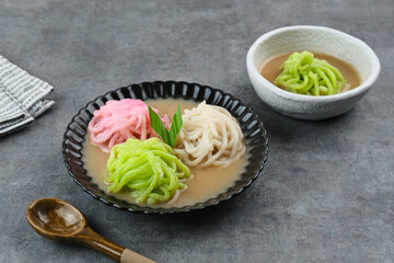Kue Putu Mayang is traditional Indonesian snack made from rice flour strands curled up into a ball, served with coconut milk and palm sugar. Selected focus.
