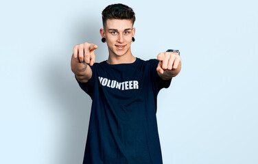 Fototapeta premium Young caucasian boy with ears dilation wearing volunteer t shirt pointing to you and the camera with fingers, smiling positive and cheerful
