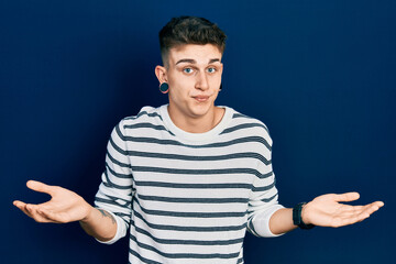 Young caucasian boy with ears dilation wearing casual striped shirt clueless and confused...