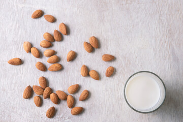 Close up top view of healthy almond milk in drinking glass and almond seed  on white wooden table...