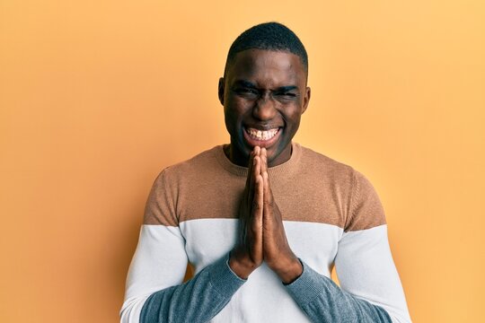 Young african american man wearing casual clothes praying with hands together asking for forgiveness smiling confident.