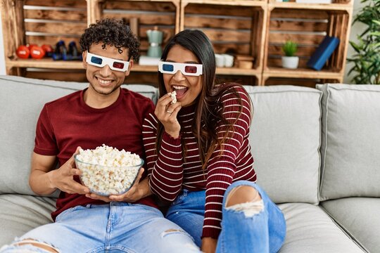 Young latin couple smiling happy sitting on the sofa at home.