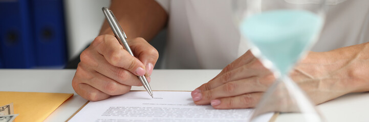 Female hand puts signature in contract at workplace