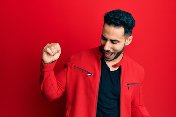 Young hispanic man wearing red leather jacket dancing happy and cheerful, smiling moving casual and confident listening to music