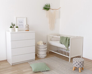 White stylish modern scandi baby's room interior with baby bed and chest of drawers. Children's...