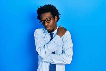 Young african american man wearing business clothes hugging oneself happy and positive, smiling confident. self love and self care