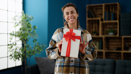 Fototapeta premium Middle age hispanic woman smiling confident holding gift at home