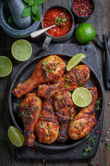 Hot roasted chicken leg served with lime and sauces.