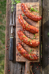 Hot roasted sausages on wooden plate in garden.