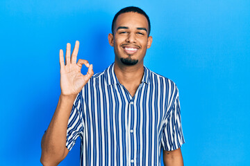 Naklejka premium Young african american man wearing casual clothes smiling positive doing ok sign with hand and fingers. successful expression.