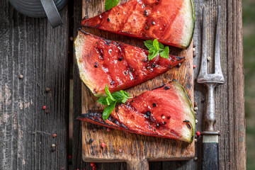 Tasty grilled watermelon on grill grate with fire.