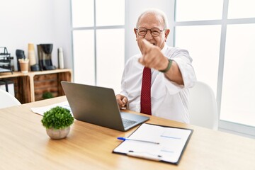 Senior man working at the office using computer laptop pointing displeased and frustrated to the camera, angry and furious with you