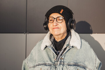 an elderly woman with headphones; it's cold, sanset