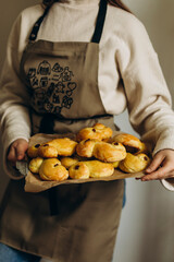 Young woman in the kitchen apron holds a tray with buns in her hands. Saffron buns in female hands....