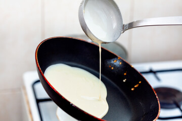 Pancakes in the pan .  Hot pan pours pancake dough with ladle