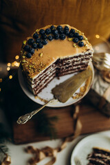 Pistachios and blueberries on the top of the cake. Crushed pistachios on salty caramel. Biscuit cake with salt caramel decorated with pistachio and blueberries.	
